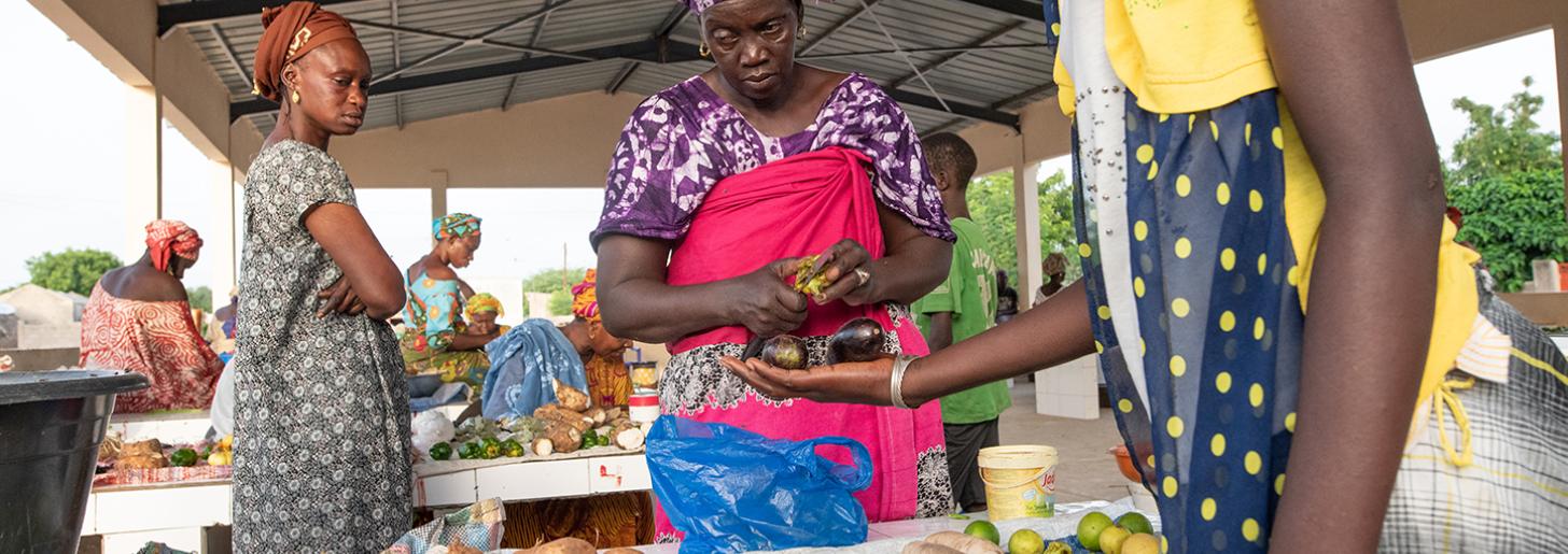Mme Astou Gueye sells product at her stall with two clients