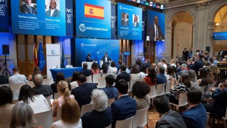 Audience seated at a World Bank Group event in Madrid, with speakers on stage, large screens displaying World Bank Group and Spain branding, and Spanish and European Union flags beside the podium.